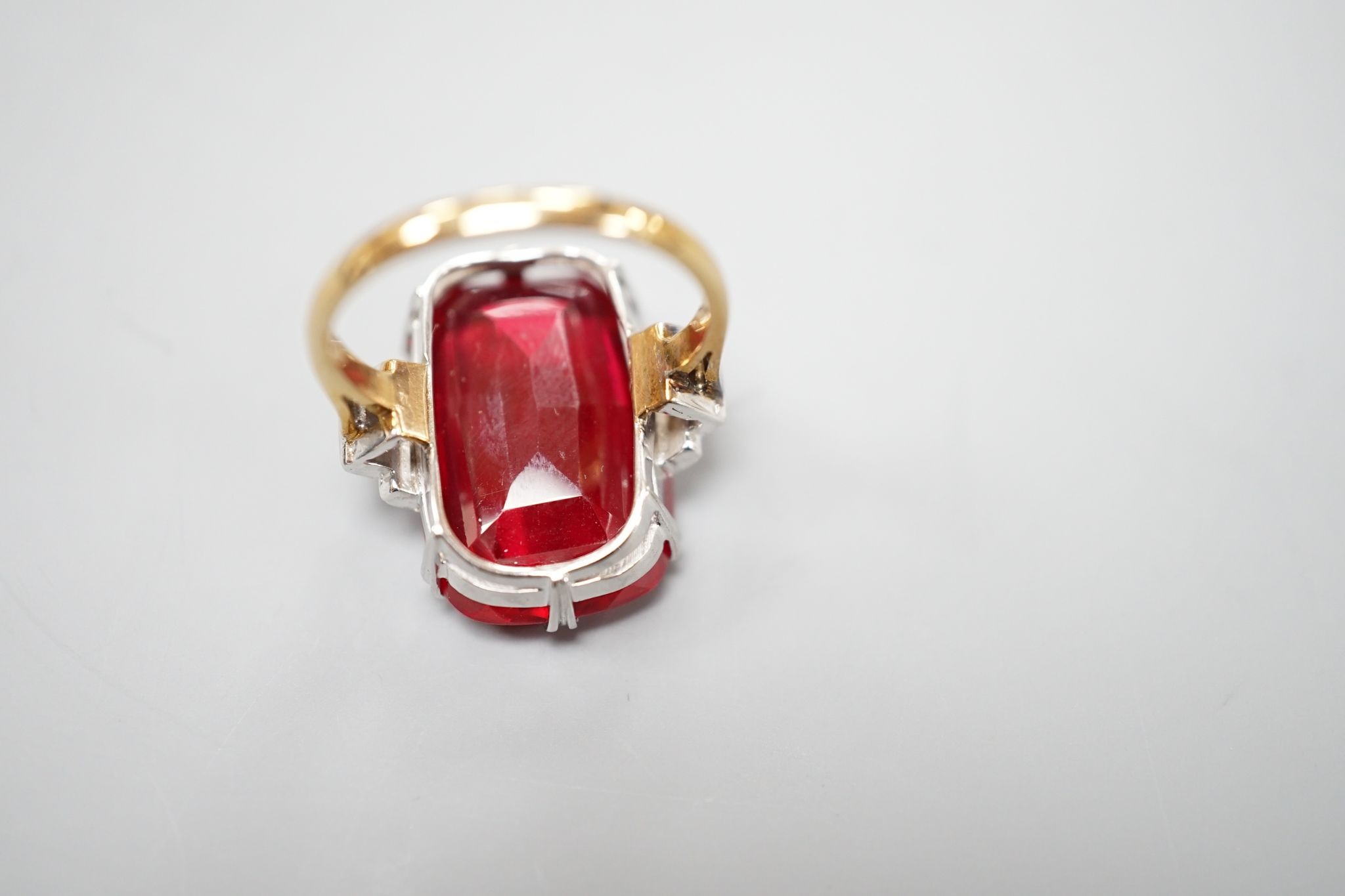 A yellow metal and large synthetic ruby set dress ring, with rose cut diamond set stepped shoulders, size L/M, gross weight 8 grams.